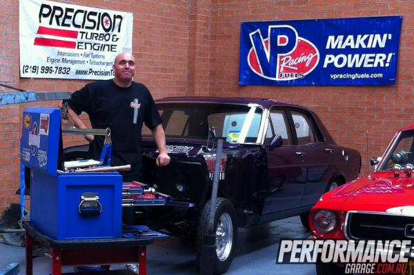 man in shop with an old muscle car