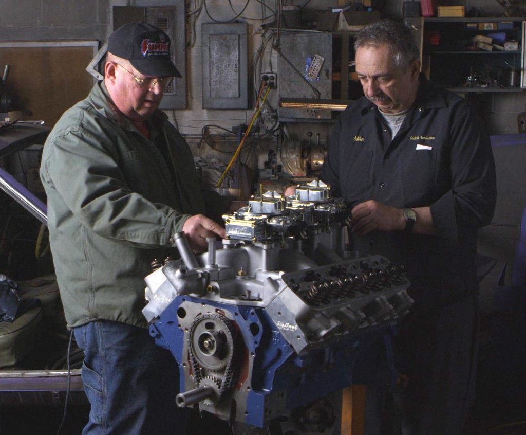 two men working on an old ford engine