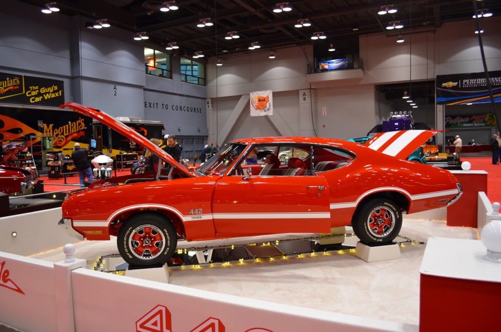 orange and white Oldsmobile cutlass 442 displayed at indoor car show