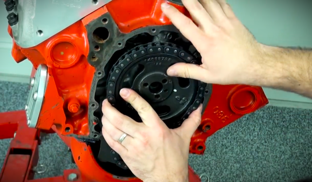 man installing a timing gear and chain onto a v8 engine