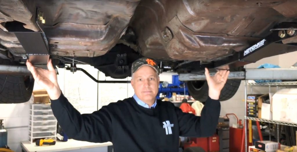 man holding subframe connectors under a car
