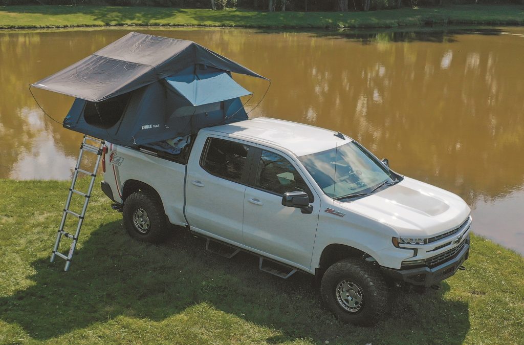 chevy silverado with rooftop tent deployed near lake