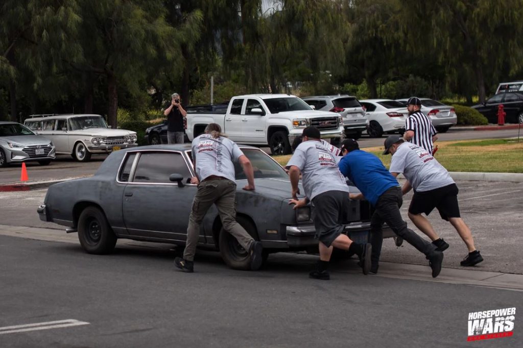 men pushing oldsmobile cutlass g body project car