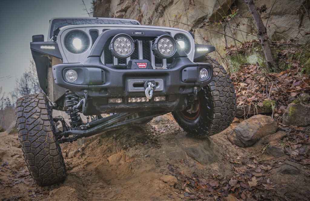 jeep wrangler JK climbing up a muddy hill trail