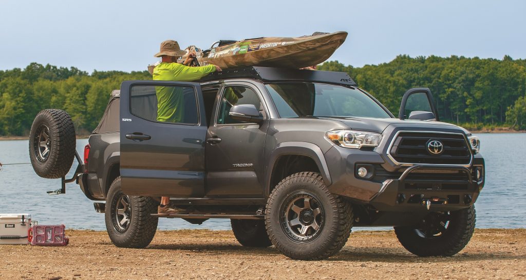 man loading a kayak onto the roof of a truck