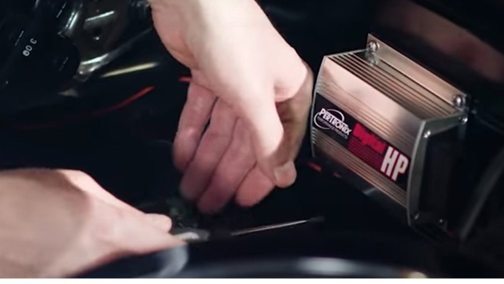 man installing a pertonix ignition controller box on the firewall of a vintage car