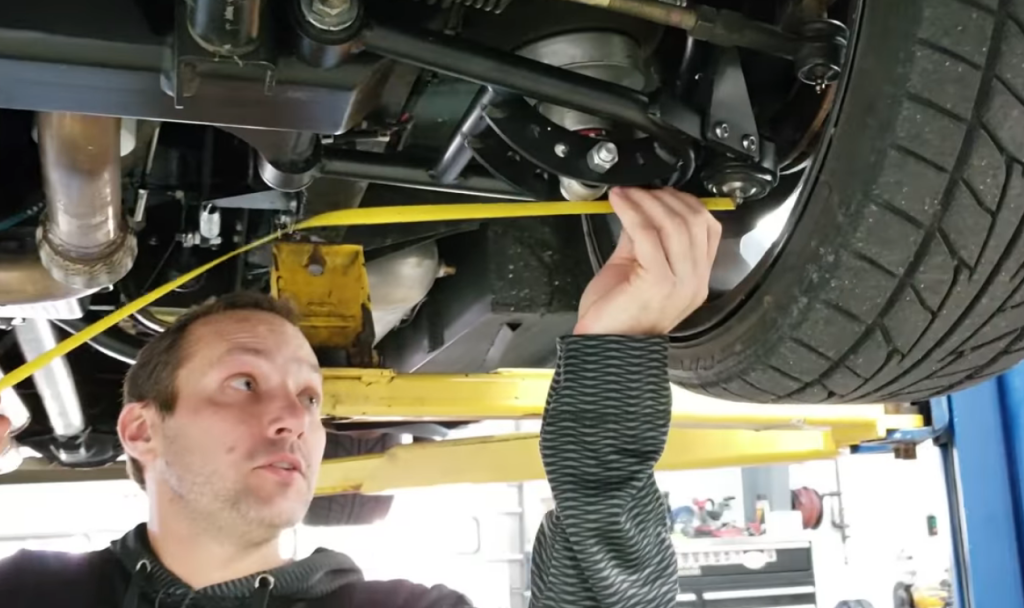 man measuring control arm length to determine vehicle suspension spring rates