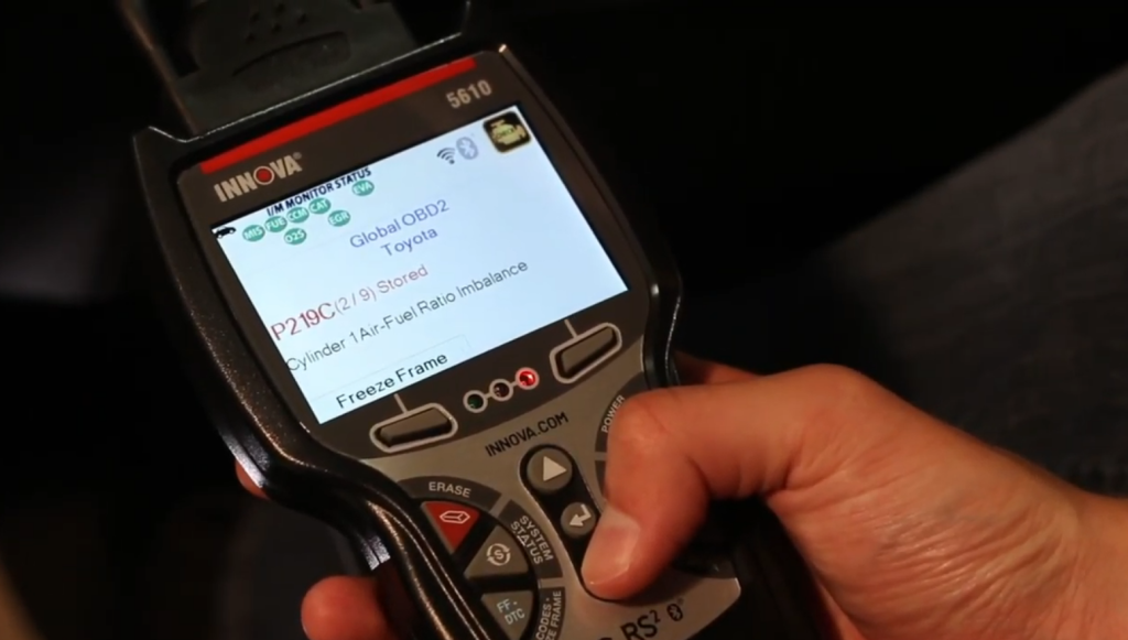 person using an innova diagnostic code reader on a car engine