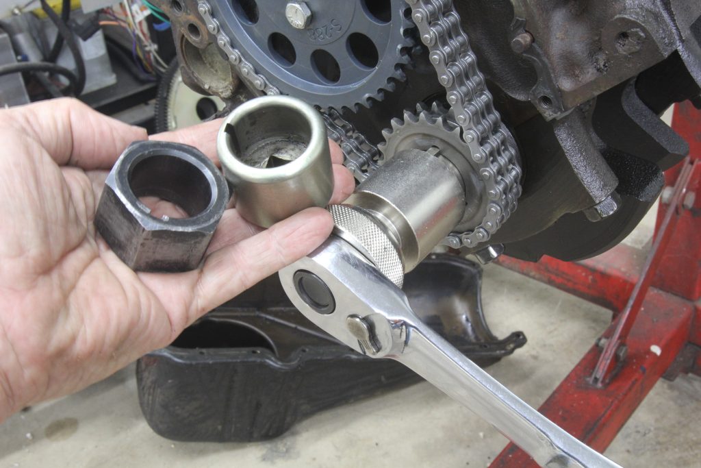 man holding nuts & collars near an engine timing chain