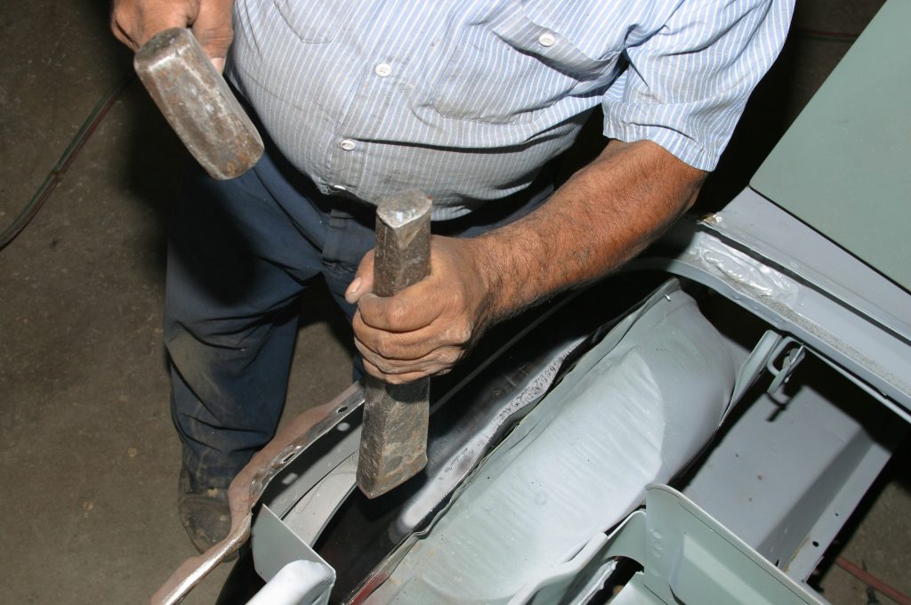 using a steel hammer to form sheetmetal in a car