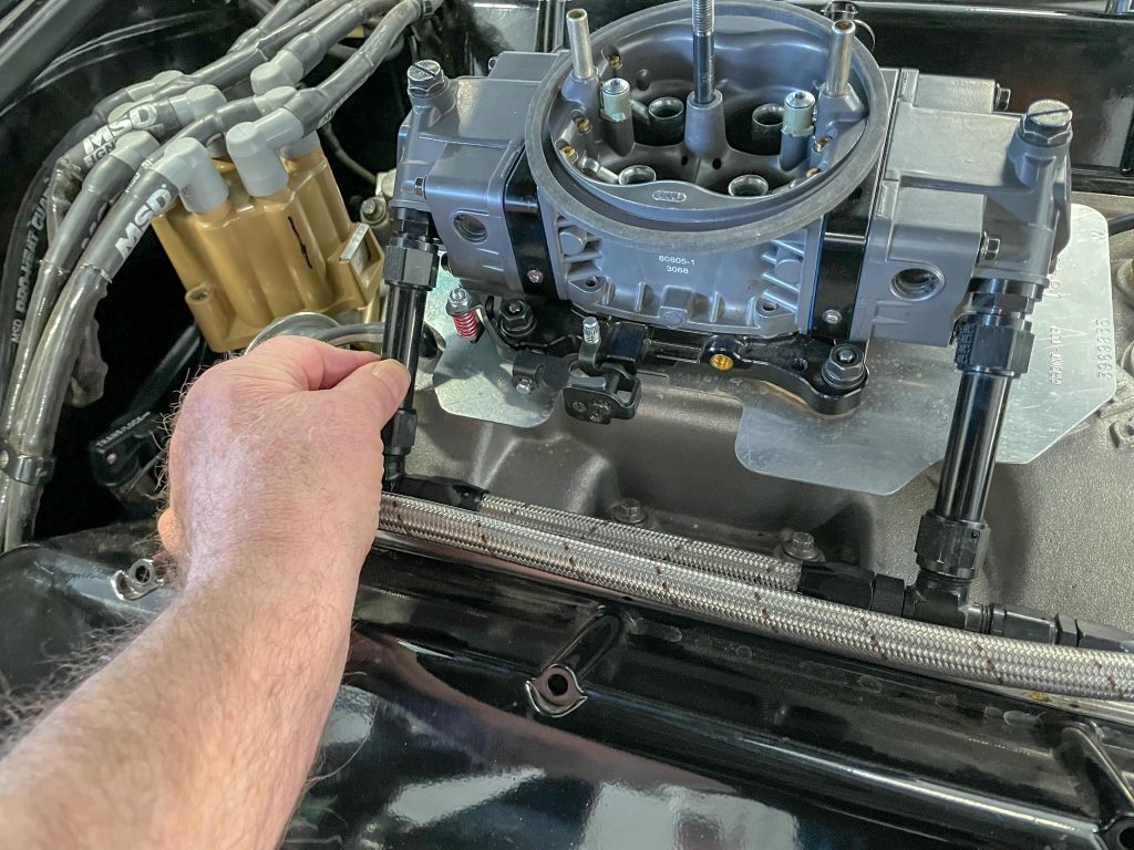 man holding fuel line for a carburetor near engine