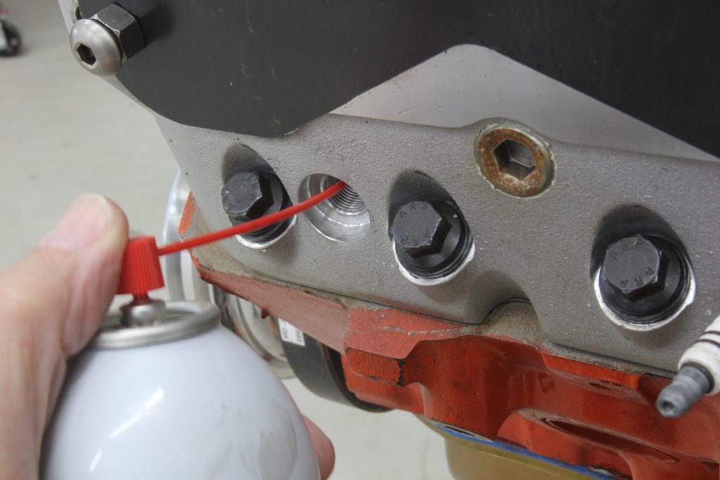 spraying lube into a spark plug hole