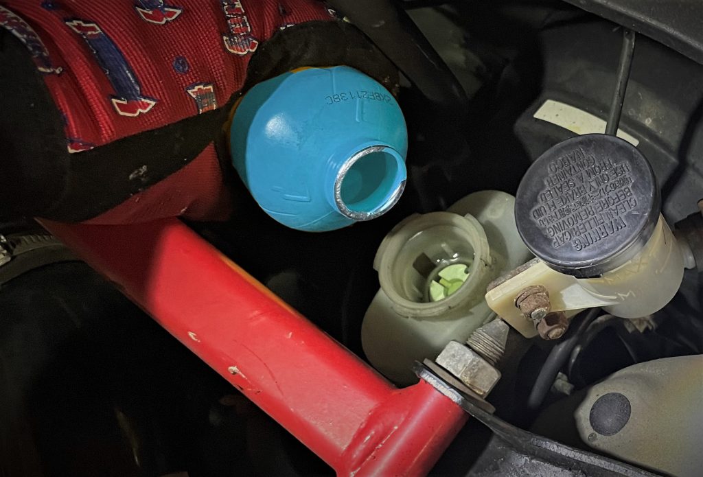 man pouring brake fluid into car master cylinder