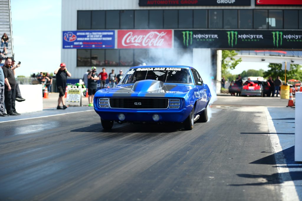 blue camaro dragster doing a burnout at track