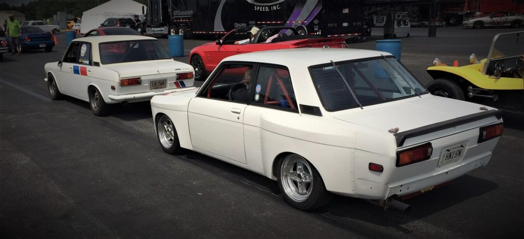 a pair of nissan datsun 510 autocross cars before a race