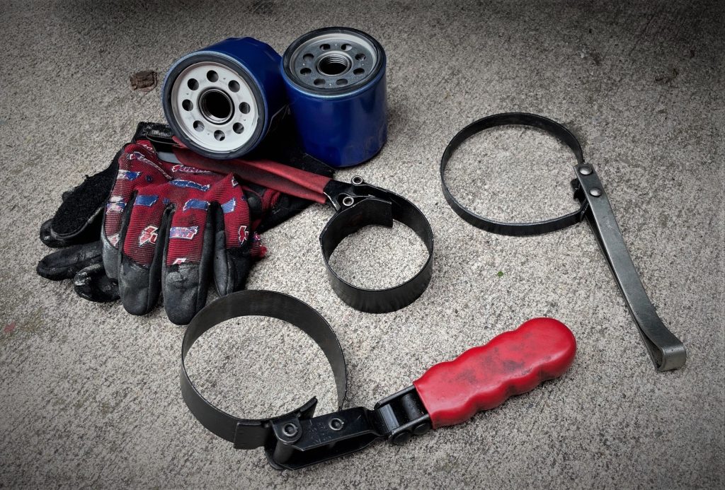 oil filter wrenches, gloves, and filters arranged on ground
