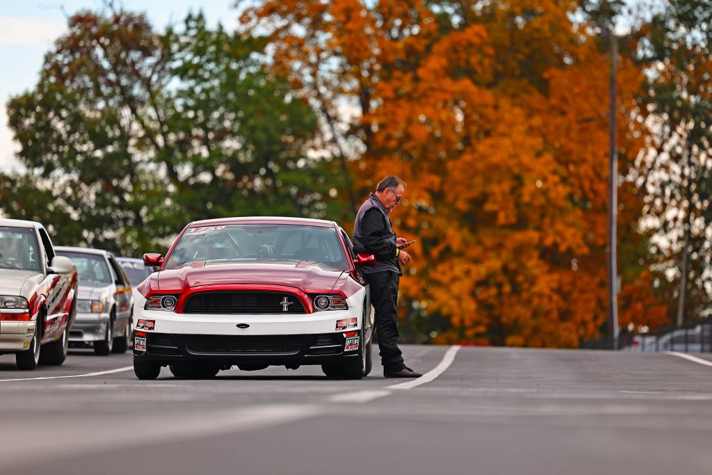 man leaning up against race car in staging lane