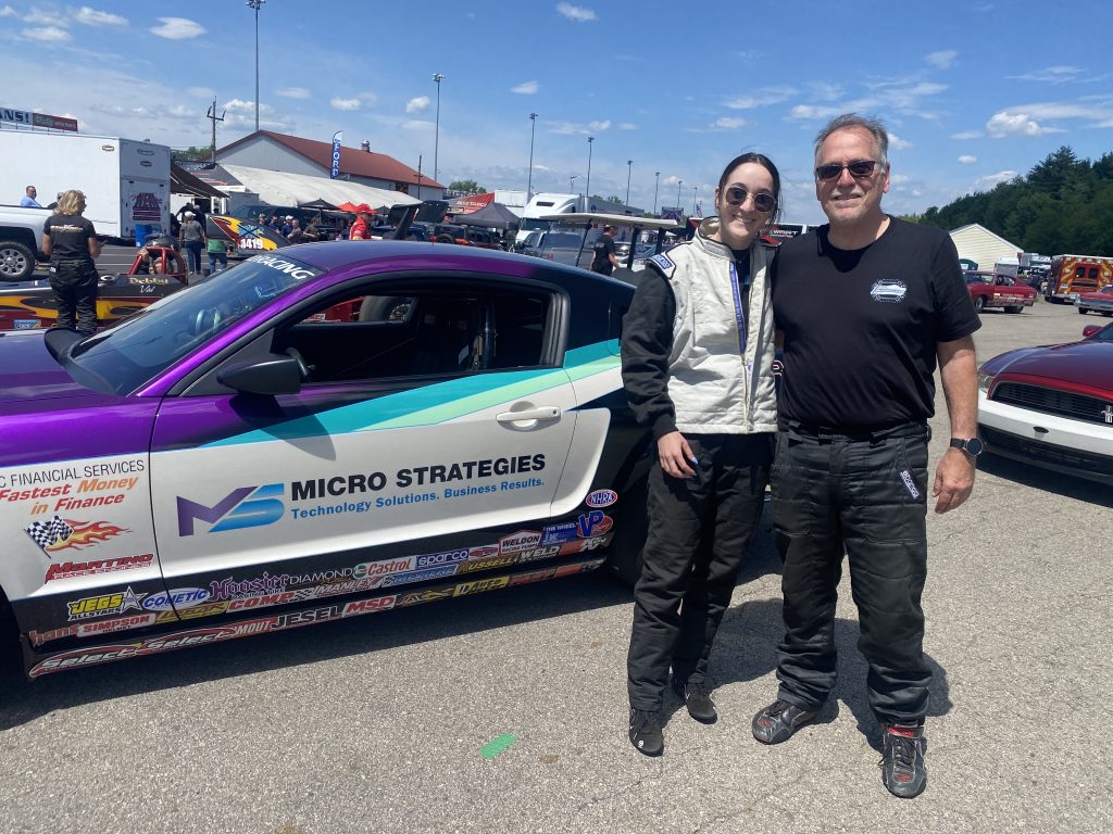 father & daughter standing near mustang race car