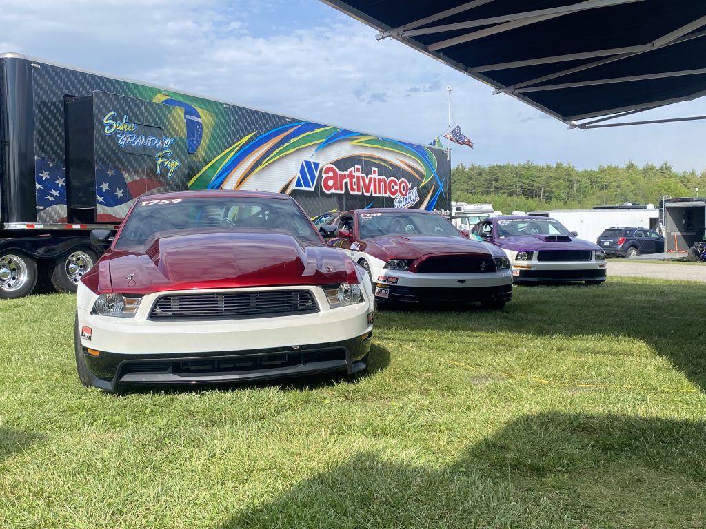 3 drag race ford mustangs in a row near pit trailer