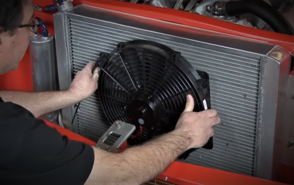 man mounting a fan to an auotmotive radiator