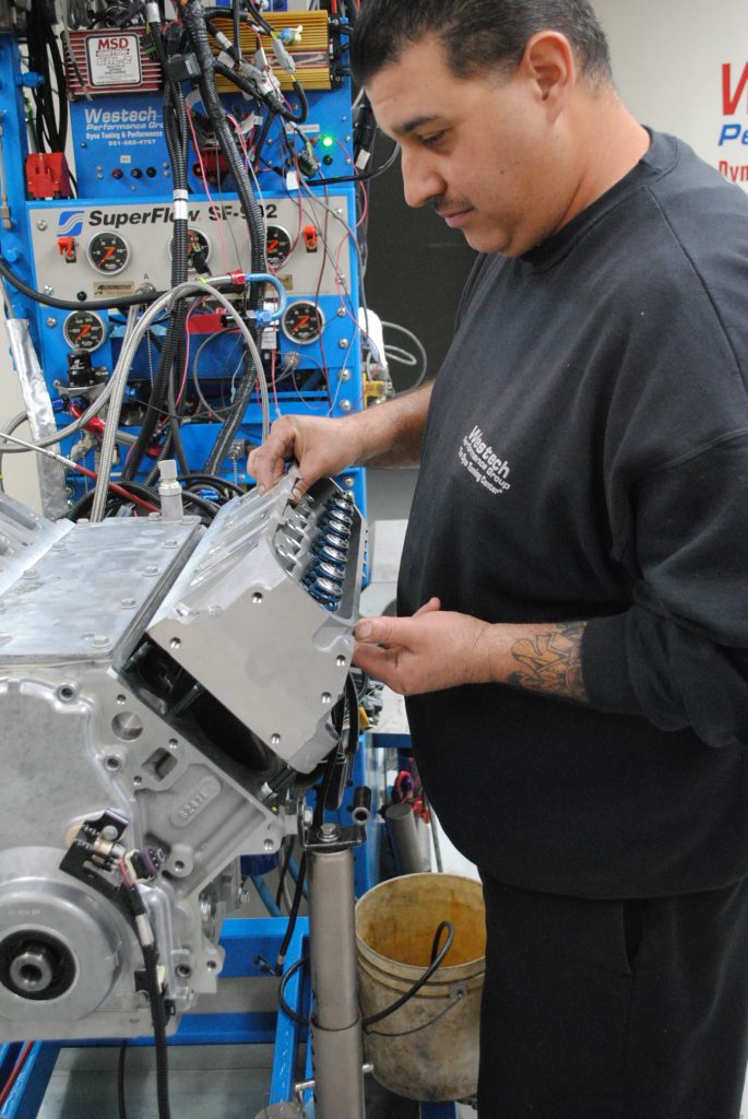 man placing cylinder heads onto an LS engine