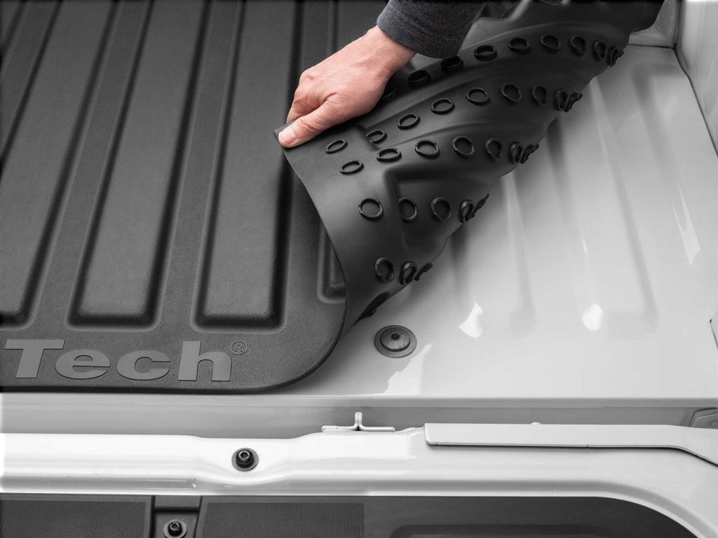 man holding up truck bed mat to show underside