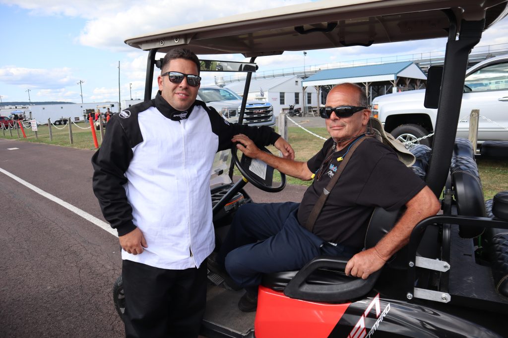 two men at race track near a golf cart