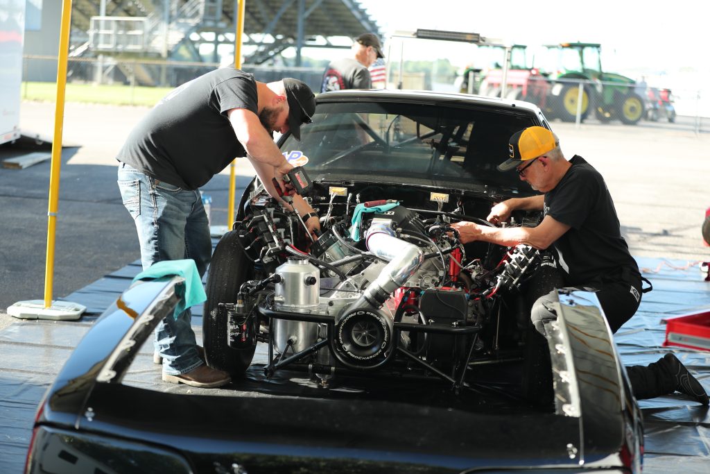 men working on an engine in a drag race car