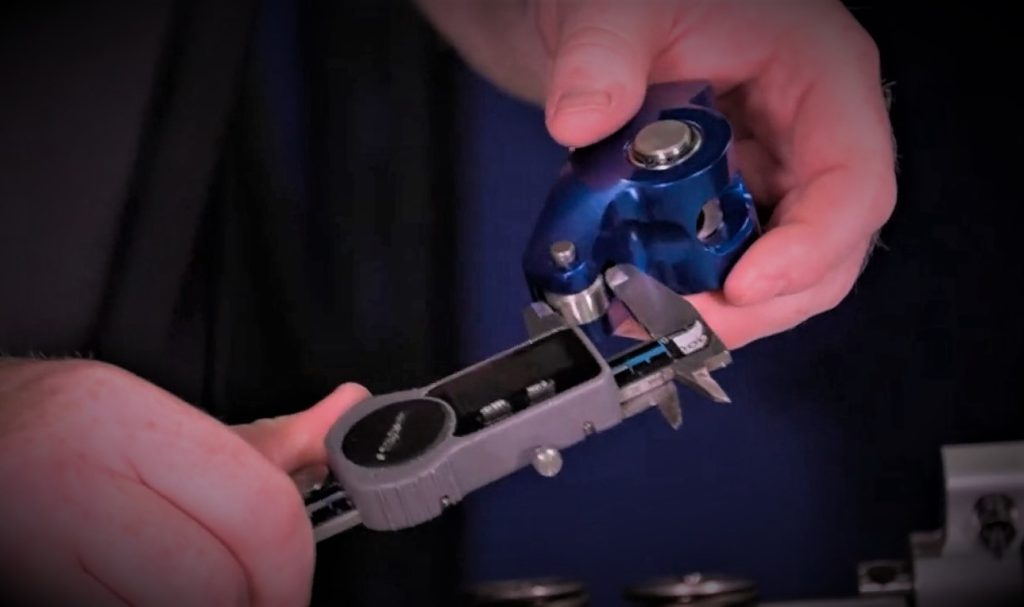 man measuring a rocker arm with a digital caliper