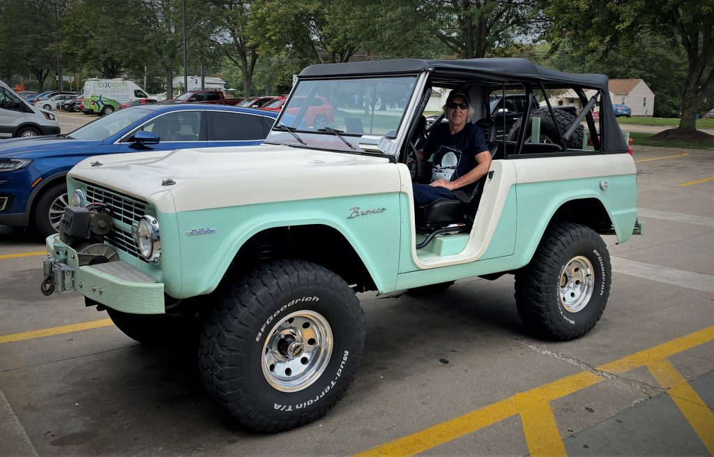 man sitting in front seat of a 1975 ford bronco