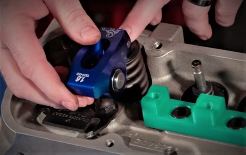 man fitting a rocker arm onto a cylinder head