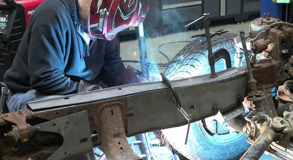 man welding on a truck frame repair patch