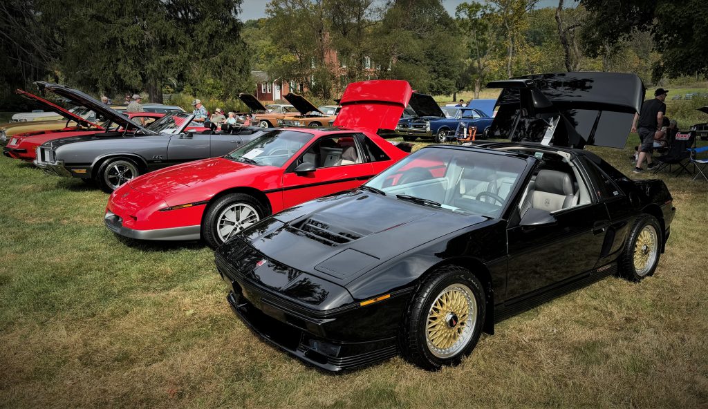 a pair of pontiac fieros at a concours show