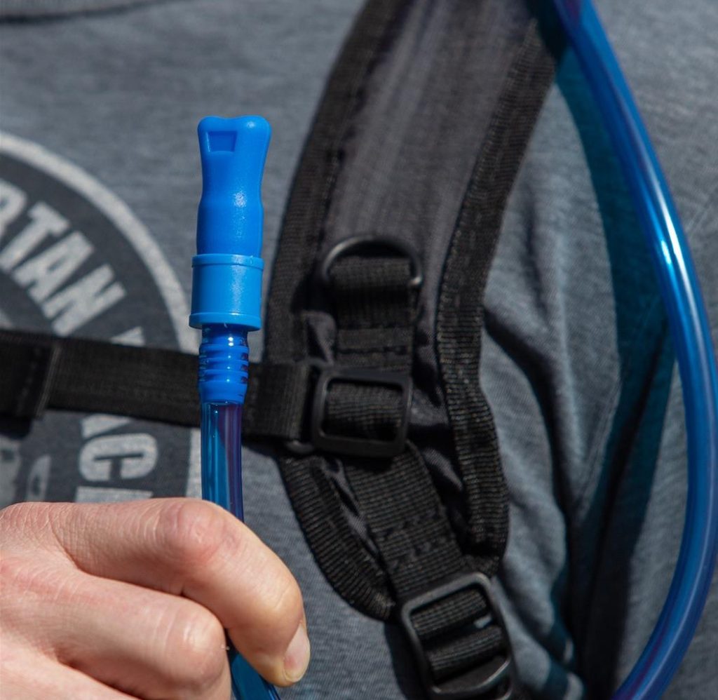 man holding mouth nozzle to hydration backpack