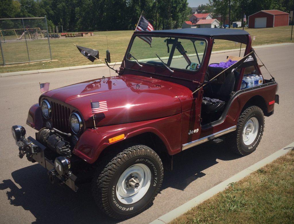 Jeep CJ-5 in parade staging area with American Flags