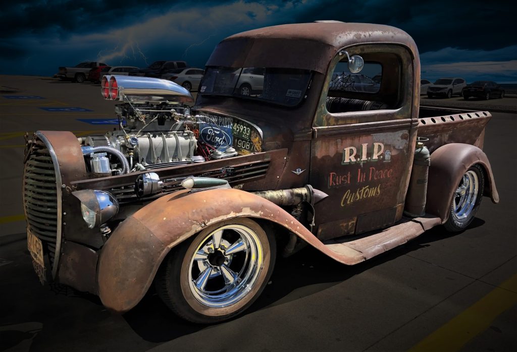 rat rod in parking lot with lightning in background