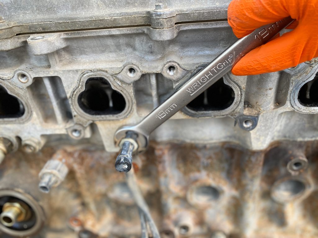 wrench turning a bolt on an engine block