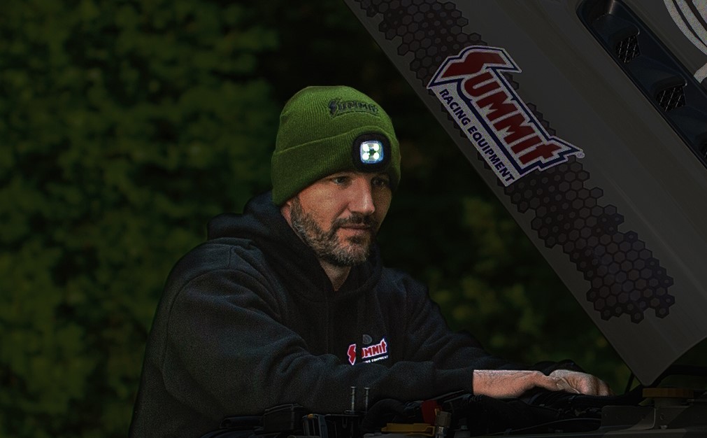 man wearing lighted winter hat while working on engine at night