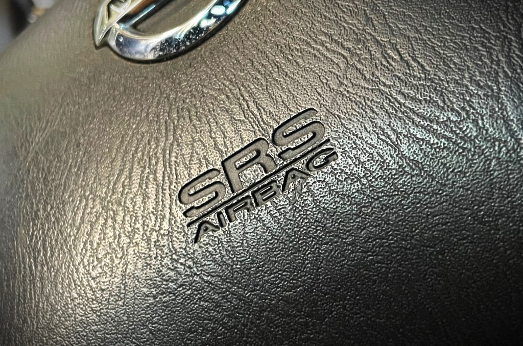 close up of srs airbag logo embossed on a steering wheel