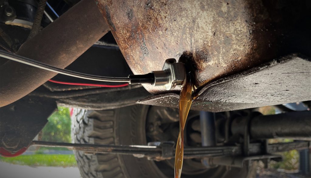 Oil drain plug being removed from engine