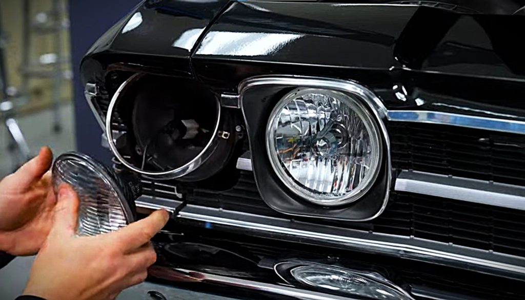 man removing headlight from a classic car