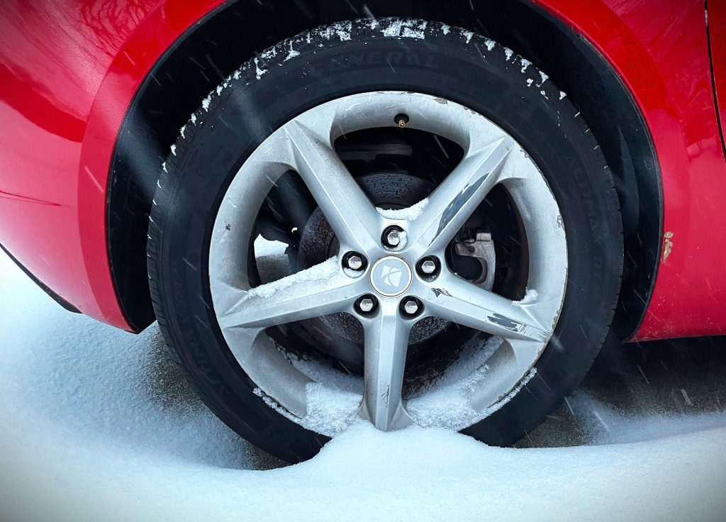 close up of a sports car wheel covered in snow