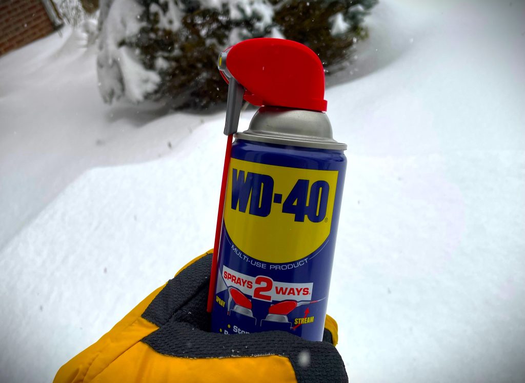 man holding can of wd40 in the snow